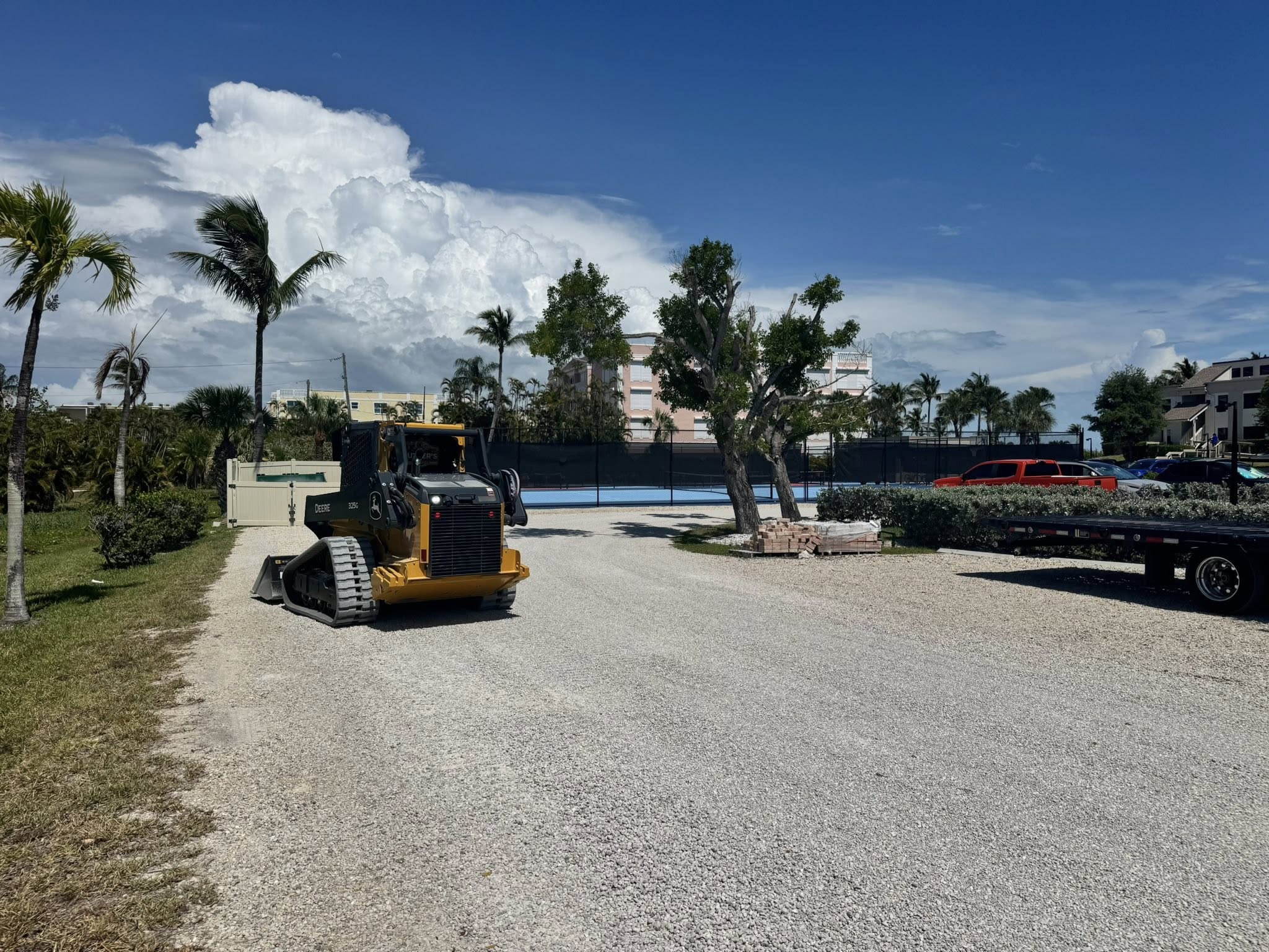 John Deere 325G track loader grading a gravel driveway at a Florida job site