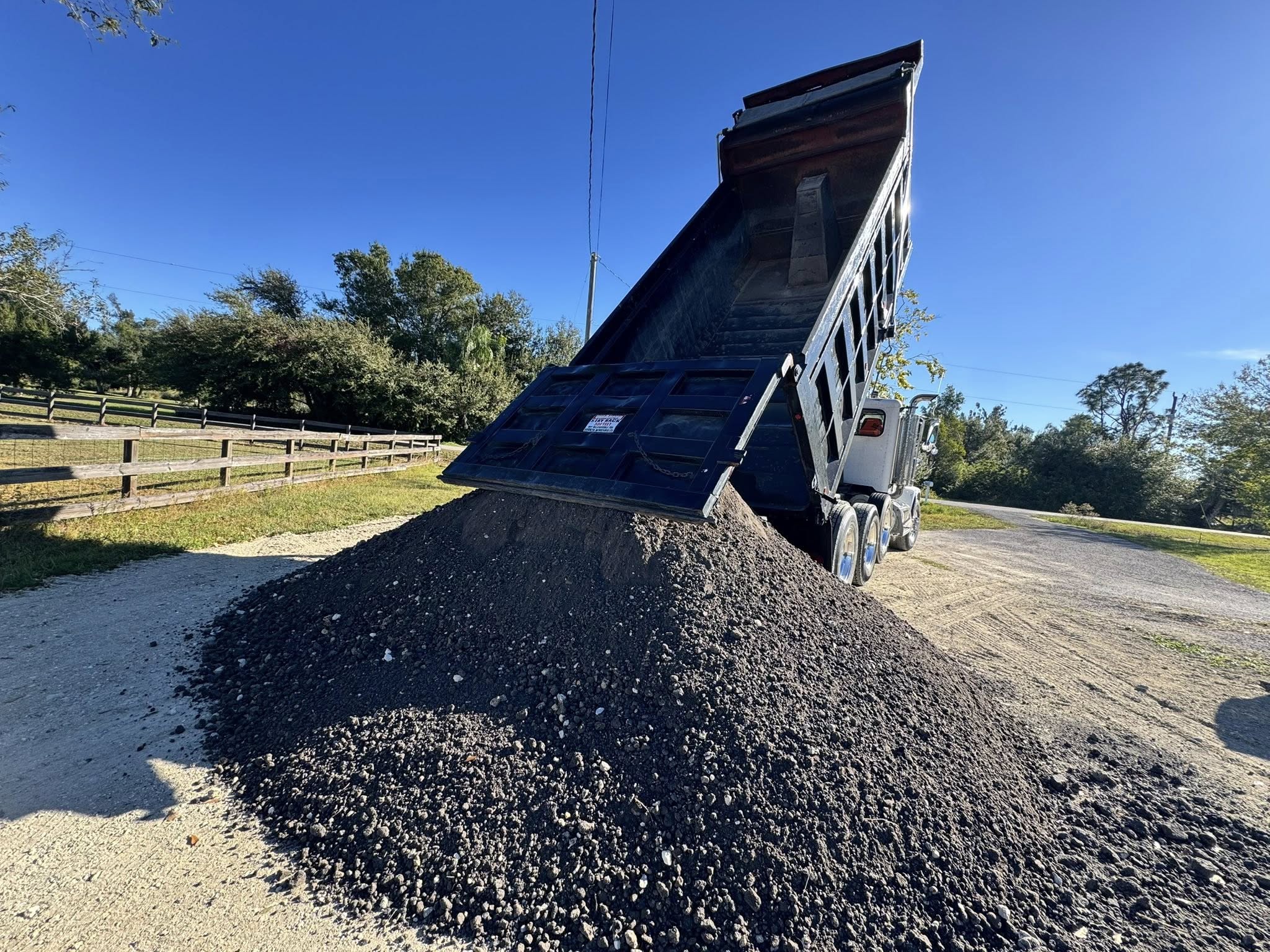 Dump truck unloading a large pile of gravel aggregate at a Florida job site